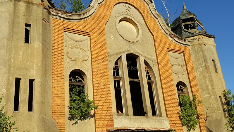Unter dem Segmentbogen ist das Glück Auf Symbol, darunter ein großes Rundbogenfenster. - Stand Juni 2019 Kohlenkirche: Waschkaue Außen